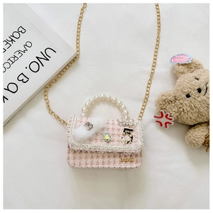 Close-up of pink tweed girl's mini crossbody bag with pearl handle and rhinestone crown
