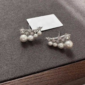Detail of silver pearl earrings with sparkling zircons on textured display pad
