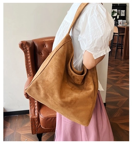 Close-up of caramel suede tote bag worn over the shoulder in a bright interior