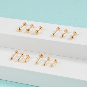 Macro shot of twelve golden surgical steel flat back stud earrings on white stands