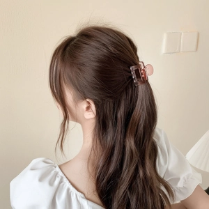 Transparent pink square hair claw clip for women shown on a model hair bun