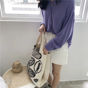 Minimalist off-white canvas tote bag with leaf print worn by model in natural light