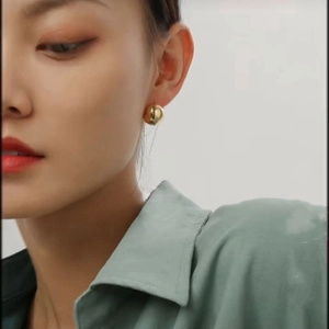 Polished gold ball stud earring on model showcasing minimalist round brass jewelry design