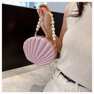 Pink shell-shaped handbag featuring sparkling fabric texture and pearl bead handle detail