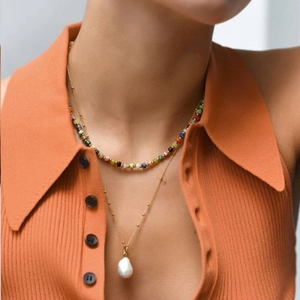 Detail of layered colorful beaded choker and long gold necklace with a baroque pearl