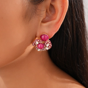 Detail of vintage flower stud earrings with rose red stones and white crystals on golden base