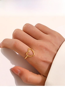 Detailed view of an adjustable gold-plated hollow heart-shaped ring worn on a finger