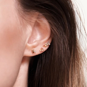 Macro shot of S925 silver studs set with colorful zircon stones on woman ear