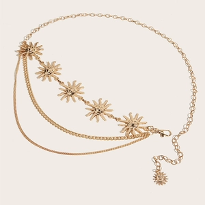 Detail van gelaagde gouden lichaamsketting met zonnehangers op een lichte achtergrond