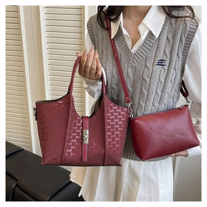 Detailed view of red PU leather tote and crossbody bag set worn by a model in bright light