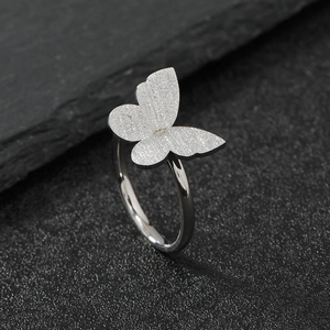 Silver stainless steel butterfly ring with frosted wings on a textured stone surface