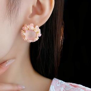 Macro detail of a 3D floral stud earring with pink resin flowers on a model