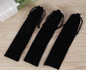 Three long black velvet drawstring pouches for fans on a light wood grain background