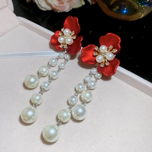 Detailed shot of red flower earrings with white pearl tassels and gold metal accents