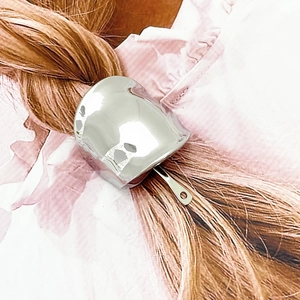 Close-up of a silver alloy hair hook accessory styled on reddish-brown hair