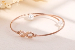 Detail van een roségouden infinity-armband met parels en geweven metalen textuur