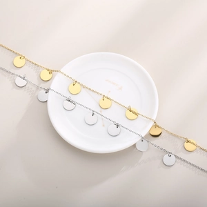 Minimalist gold and silver stainless steel necklaces with round disc charms on a white tray