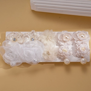 Détail de boucles d'oreilles fleurs avec pétales en tissu, perles et cristaux