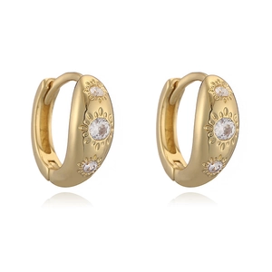 Détail de boucles d'oreilles créoles dorées avec étoiles en zircone sur fond blanc