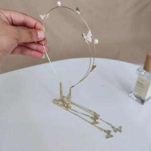 Detail of gold headband with rhinestone butterflies, pearls and long tassel chains