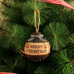 Détail d'une boule de Noël en toile de jute avec motif à carreaux verts et texte festif