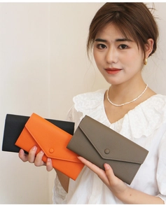 Vergleich von langen Lederbrieftaschen in Schwarz, Orange und Taupe mit Kieselmaserung