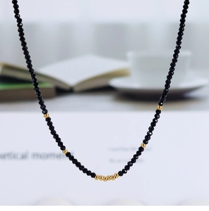 Close-up of black faceted beads and gold metal beads on a luxury minimalist necklace