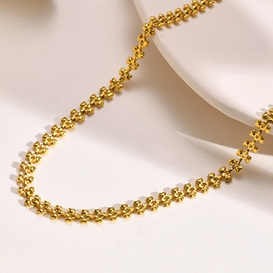 Detailed view of gold wheat-style heart chain links on a minimalist white display