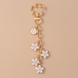 Detail of gold keychain with white cherry blossom flowers and letter U round charm