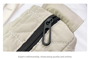 Macro shot of quilted beige tote bag showing contrast stitching and black metal zipper detail