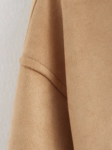 Macro shot of camel suede fabric showing exquisite stitching detail and premium texture