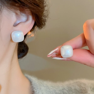 Close-up of square pearl earrings showing glossy texture and worn on the ear model
