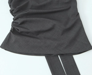 Dettaglio del tessuto grigio scuro con trama saia e drappeggio sulla maglia con spalline