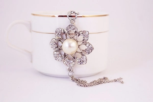 Close-up of pearl flower pendant with crystals on white ceramic cup for bag keychain