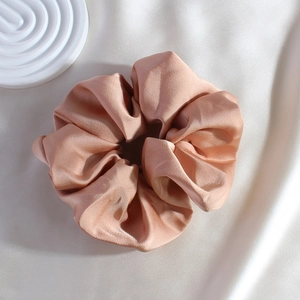 Close-up of a premium pink satin scrunchie with a soft silk texture and elegant shine