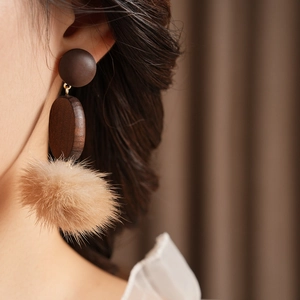 Detail of vintage earring featuring dark wood circle and soft khaki faux fur pompom
