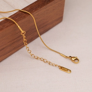 Macro shot of gold stainless steel snake chain with lobster clasp and S.STEEL engraved tag