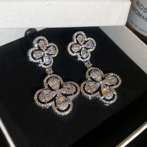 Macro shot of silver-colored four-leaf clover drop earrings with crystal pavé stones