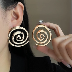 Detailed view of oversized golden spiral textured earrings worn by a model