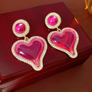 Vintage luxury magenta heart earrings with gold trim and white rhinestones on a jewelry box