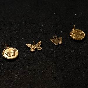 Detail of four golden metal butterfly and medallion pendants on dark textured background