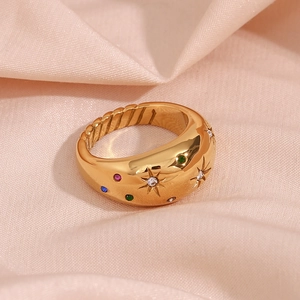 Macro detail of 18K gold-plated dome ring with colorful gemstone star engravings