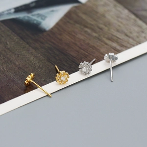 Macro side view of micro-set flower earrings in gold and silver with zircon centers