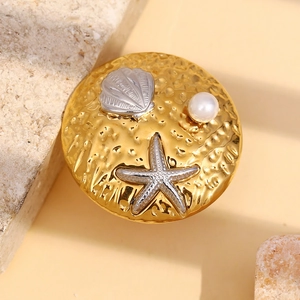 Detailed macro view of 18K gold starfish and pearl design on a textured round ring