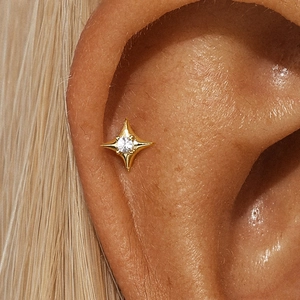 Close-up of a gold s925 silver star earring with a clear gemstone on the ear