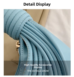Close-up of sky blue leather handbag featuring pleated knot handle and golden zipper detail