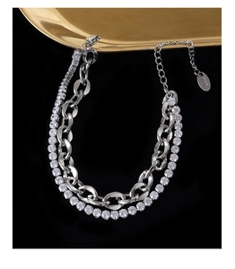 Gros plan du bracelet double chaîne avec zircons brillants et étiquette K18 sur fond noir