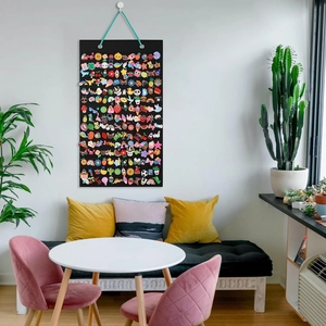 Wall-mounted black felt pin display banner showing colorful cartoon enamel badges in a living room