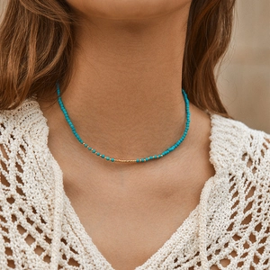 Bohemian turquoise bead necklace with gold accents worn on a model in summer light