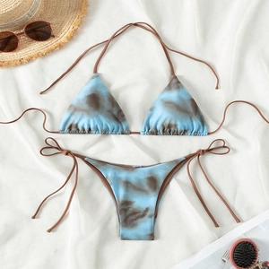 Flat lay of blue and brown tie-dye bikini set with straw hat and sunglasses accessories